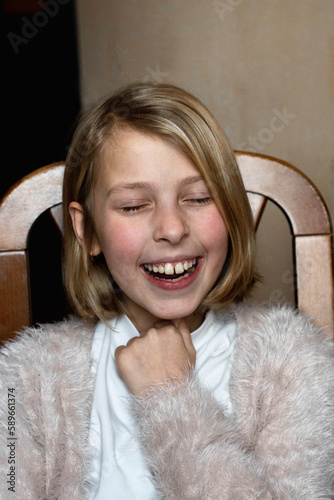 Smiling pretty blonde hair girl sitting on the chair inside the room