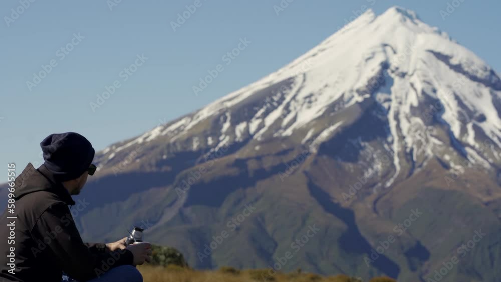 Young man pouring water on argentinian drink called mate in Mount Taranaki, New Zealand Young man pouring water on argentinian drink called mate in Mount Taranaki, New Zealand