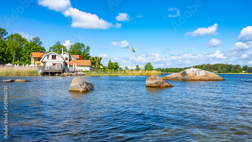 Sunny day in a small village bay on Vaxholm Island. On the coast is the Hembygdsgard Museum and a tranquil terrace with seating areas for guests. Stockholm Archipelago, Sweden photo