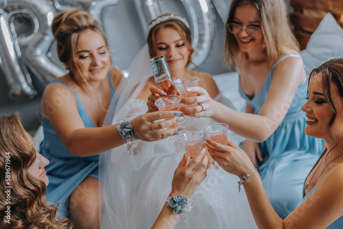 Wall Mural Young bridesmaids in blue silk dresses drink champagne in the bride's room