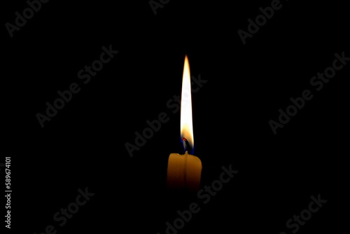 Burning candle on a black background in the dark