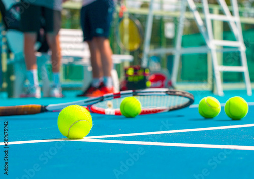 Tennis racket, ball and water bottle on hard blue court