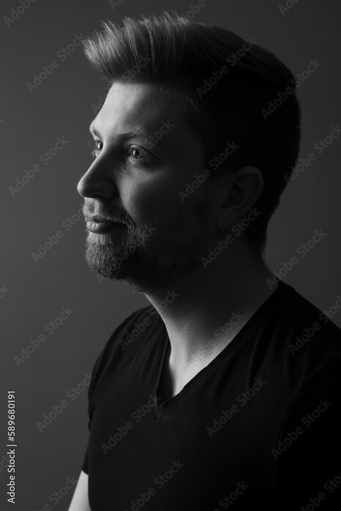 Black and white portrait of a handsome caucasian man in his 20s. This is a headshot and he is wearing a black shirt. He has light hair and a beard. 