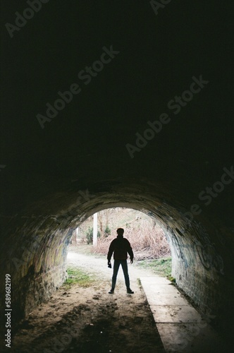 A silouette of a man standing under the tunnel in the afternoon bright light.