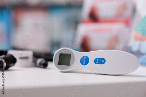 Selective focus on medical thermometer standing on table in empty pharmacy, medical instruments ready to be used by professional. Drugstore equipped with pharmaceutical products, vitamins and drugs