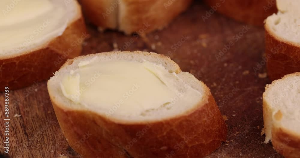 Spread butter on a soft baguette , sliced bread on which butter is spread from cream Spread butter on a soft baguette , sliced bread on which butter is spread from cream