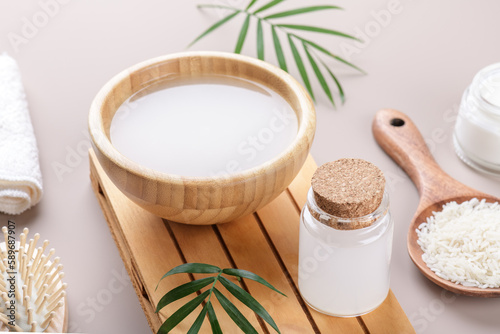Homemade cosmetic rice water with ingredients on beige background