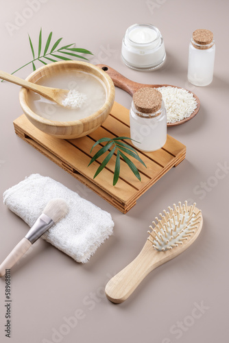 Homemade cosmetic rice water with ingredients and beauty kit on beige background, healthy beauty treatment ingredients for homemade comsetics, beauty recipe for home spa, natural skincare preparation