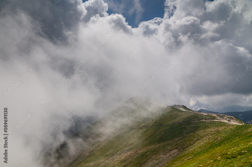 tourists on a mountain trail walks into a cloud.