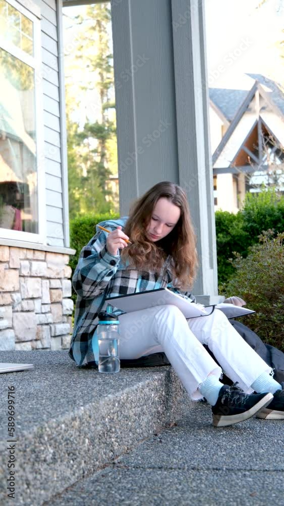 a girl draws with a pencil in a large notebook notebooks filming country house bottle of water white jeans black sneakers checkered blue jacket long brown hair of teenage girl a girl draws with a pencil in a large notebook notebooks filming country house bottle of water white jeans black sneakers checkered blue jacket long brown hair of teenage girl