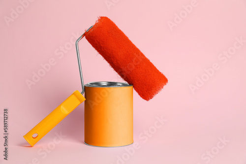 Fototapeta Naklejka Na Ścianę i Meble -  Can of orange paint and roller on pink background