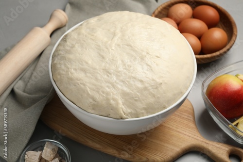 Fresh yeast dough, rolling pin and ingredients on grey table, closeup. Making cake