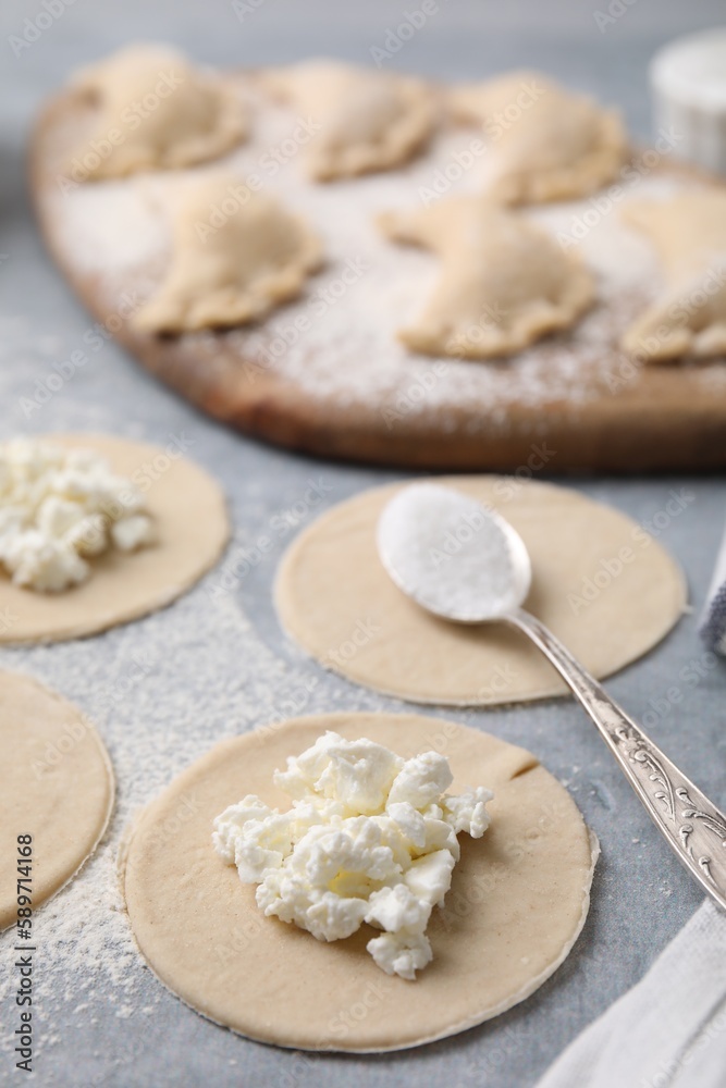 Process of making dumplings (varenyky) with cottage cheese. Raw dough and ingredients on grey table, closeup