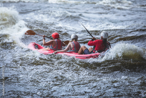 Raft boat during whitewater rafting extreme water sports on water rapids, kayaking and canoeing on the river, water sports team with a big splash of water, 3 persons in a raft boat
