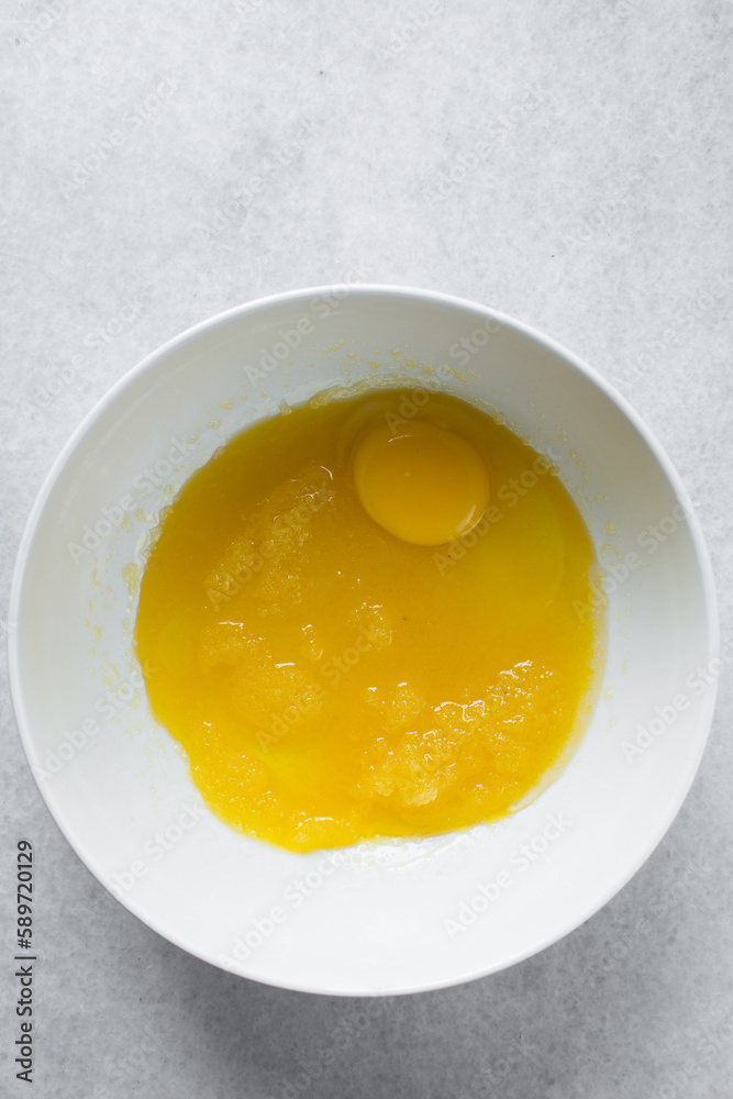 Eggs, Melted butter and sugar in a white mixing bowl, process of making muffins Eggs, Melted butter and sugar in a white mixing bowl, process of making muffins