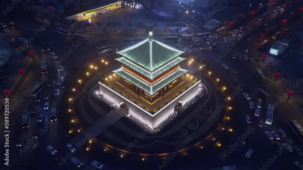 Vehicles drive in traffic circle around Bell Tower on Xian China night