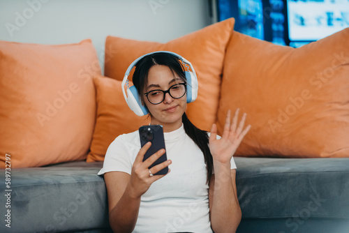 A woman doing home workout with headphones and smartphone for a video call. Reflects modern lifestyle, blending technology, health, and connectivity for holistic well-being.