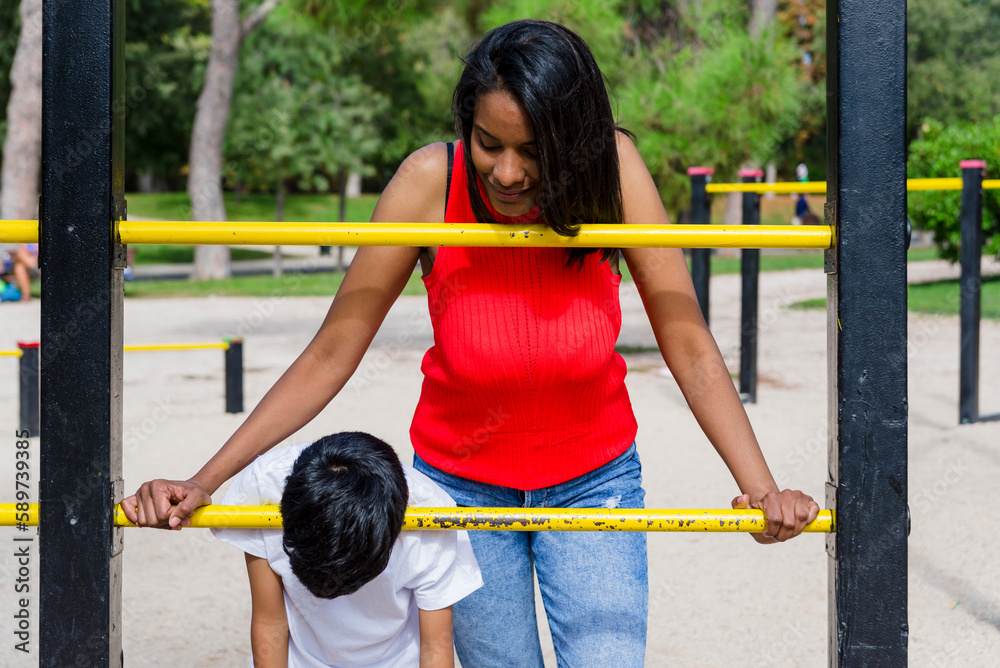 Obraz premium Mother and son enjoying playing at the playground in the park.