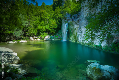 Beautiful landscape. Small lake and forest waterfall. Clear spring water. Nature background.