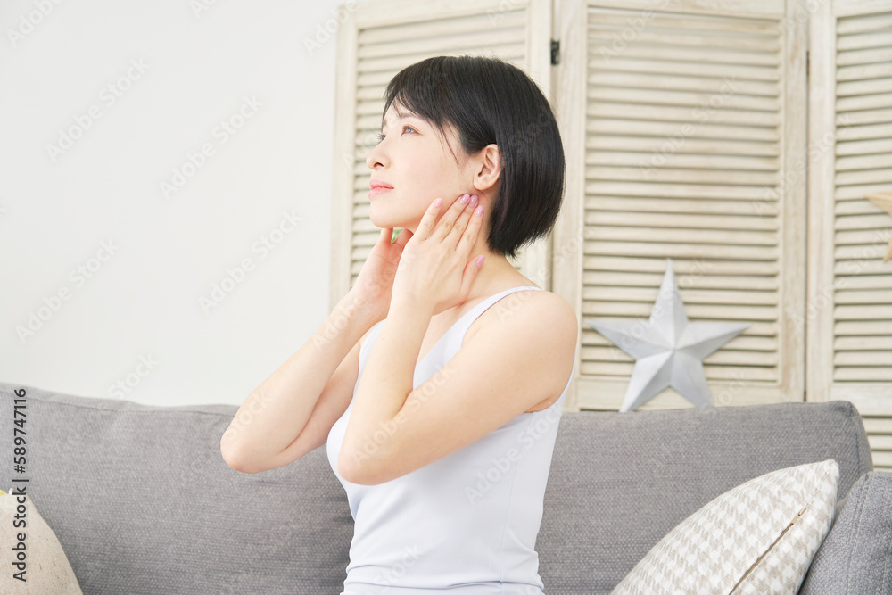 リビングで首のリンパマッサージをする女性 リビングで首のリンパマッサージをする女性