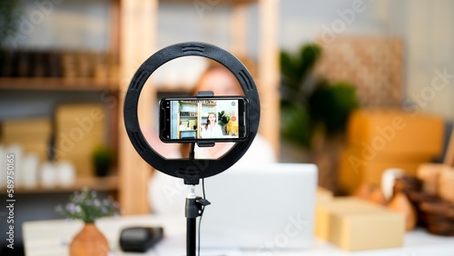 Record live video and sharing product promotion on social media with ring light and smartphone horizontal rotate and Caucasian seller woman in screen