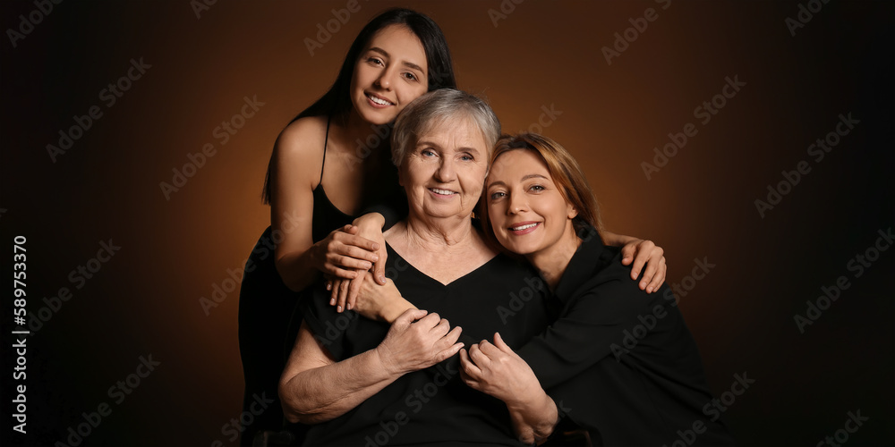 Portrait of beautiful mature woman, her daughter and mother on dark brown background Portrait of beautiful mature woman, her daughter and mother on dark brown background