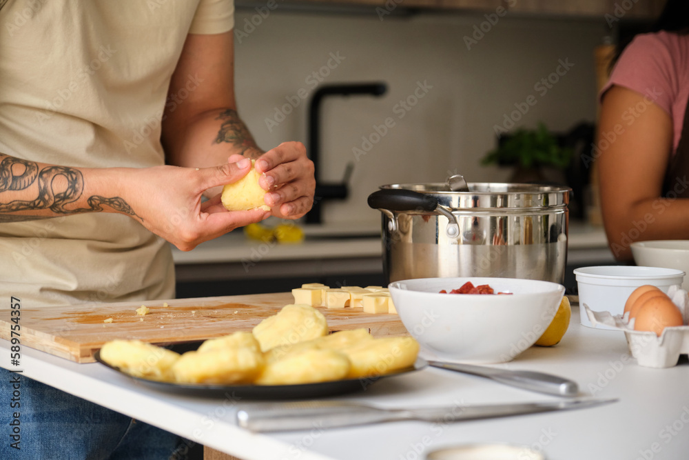 Young unrecognizable Ecuadorian man moulding llapingachos dough at kitchen.