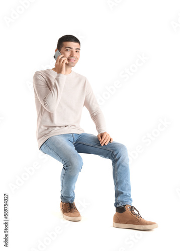 Handsome guy talking by mobile phone in chair on white background