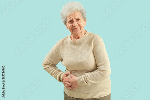 Senior woman with appendicitis on blue background