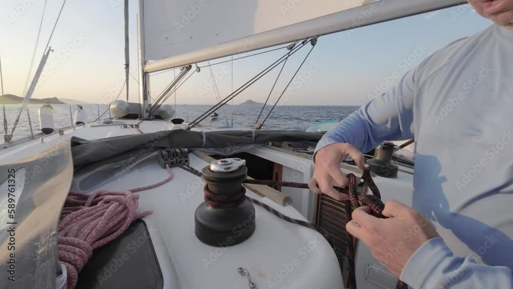 Sailor's hand on a winch of sailing boat. Man pulling ropes, winding