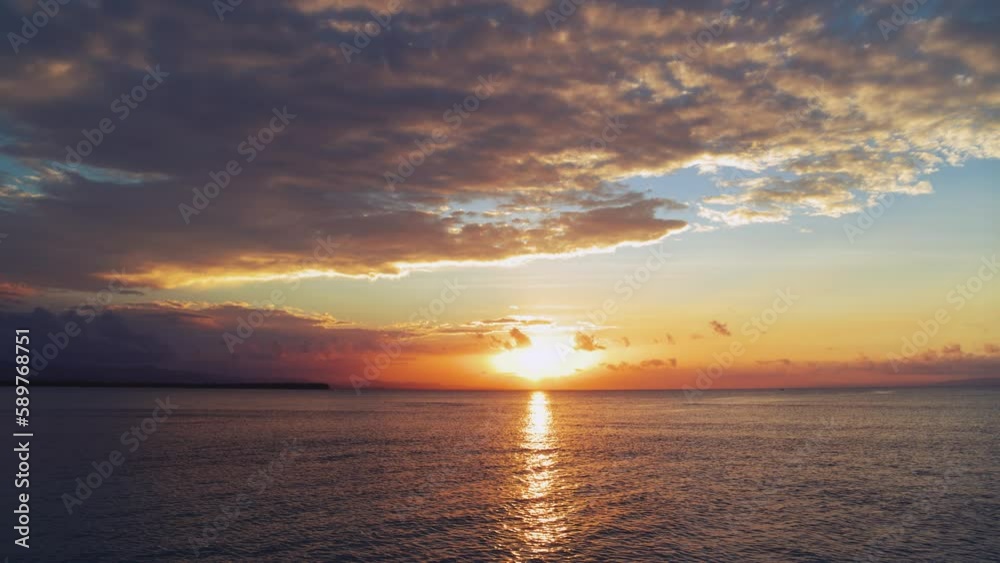 Bright background of sea sunset, view from the beach. A yellow sun in a blue sky with orange clouds over the Caribbean Sea. Beautiful evening seascape. Sun glare on the water. Twilight. Bright background of sea sunset, view from the beach. A yellow sun in a blue sky with orange clouds over the Caribbean Sea. Beautiful evening seascape. Sun glare on the water. Twilight.