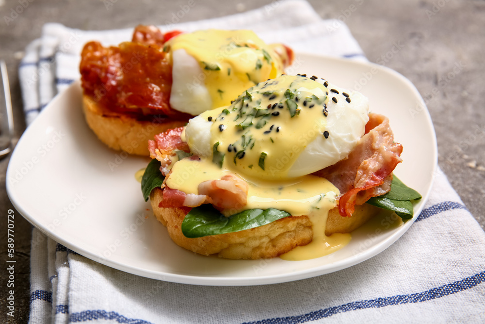 Plate with tasty eggs Benedict on grey grunge table, closeup Plate with tasty eggs Benedict on grey grunge table, closeup