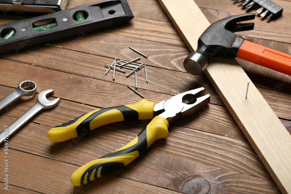 Pliers, nails, plank and hammer on wooden table Pliers, nails, plank and hammer on wooden table