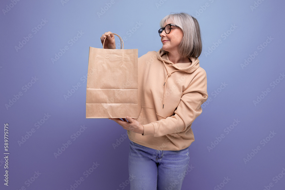 mature 60s business woman with gray hair holding social security package on studio background with copy space mature 60s business woman with gray hair holding social security package on studio background with copy space
