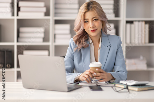Portrait of Asian business woman holding coffee cup with work in workplace office Business documents money financial planning concept