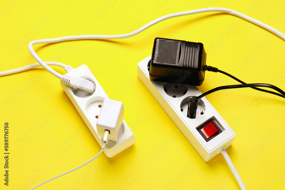 Electric extension cords with plugs on yellow background Electric extension cords with plugs on yellow background