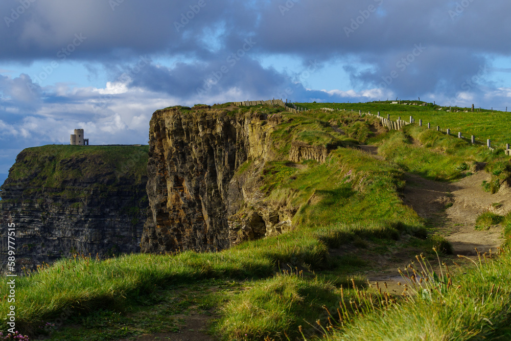 Footpath on the edge of the Cliffs of Moher at sunset with O’Brien’s tower in the distance