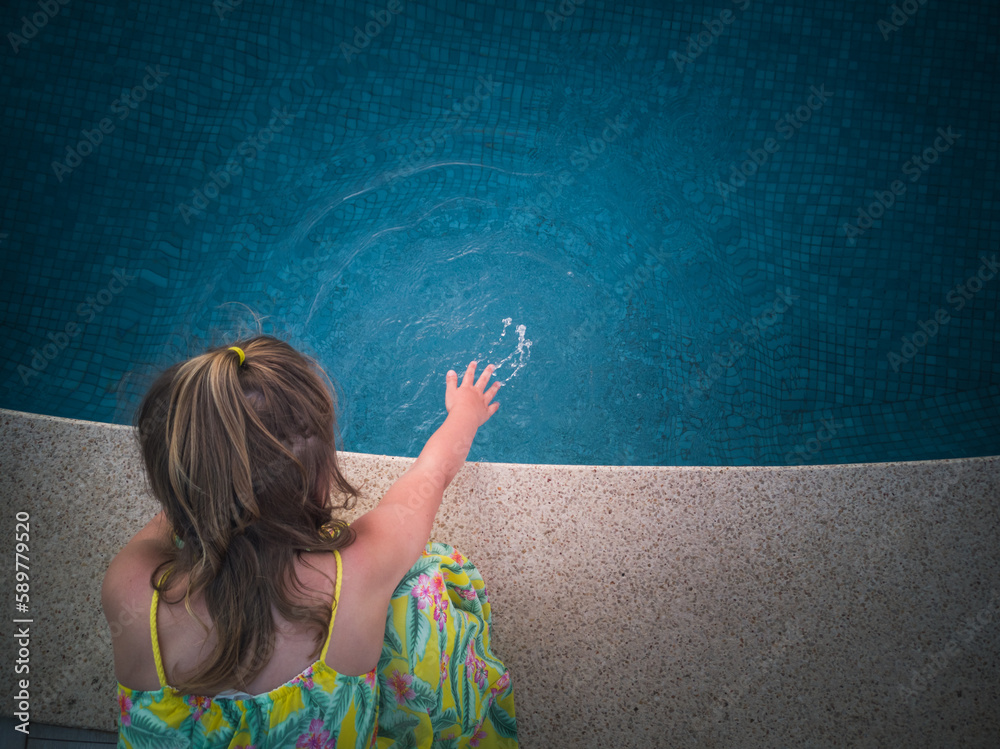A little girl checks the water condition before swimming in the pool.