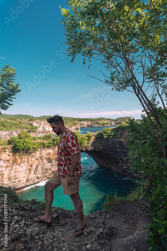 Podróżnik patrzący na piękną Broken Beach, na tropikalnej wyspie Nusa Penida, turkusowa woda i niesamowity krajobraz.