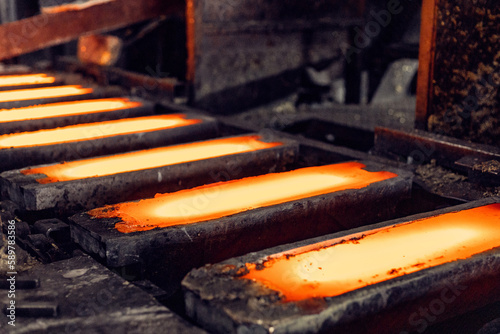molds with red-hot molten brass on a conveyor at a casting factory