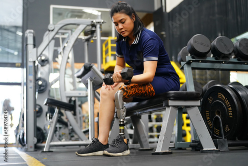 Young female with one prosthetic leg warms up by lifting light weights. Concept of living a woman's life with a prosthetic limb.