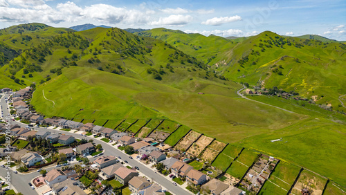 Drone photos over the city of Antioch, California on a beautiful sunny day with green hills, streets, houses, cars and solar.