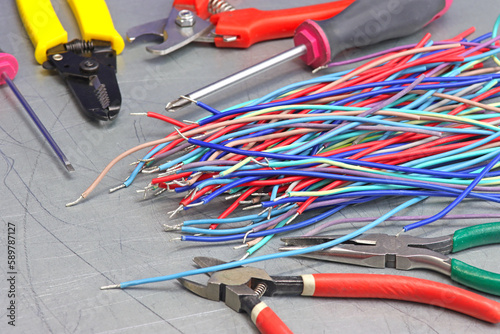 Electric tools and colored copper insulated wires on a metal surface.