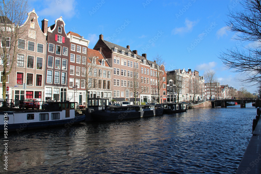 canal, river and old brick houses or flat buildings in amsterdam (the netherlands) 