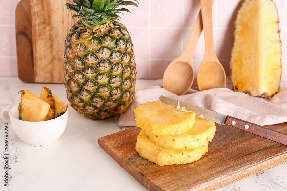 Wooden board with cut pineapple on table in kitchen Wooden board with cut pineapple on table in kitchen