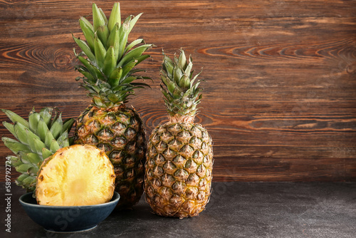 Fresh cut pineapples on black table near wooden wall