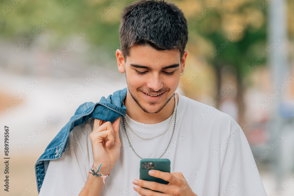 Fototapeta premium young male on the street walking looking at the mobile phone or smartphone