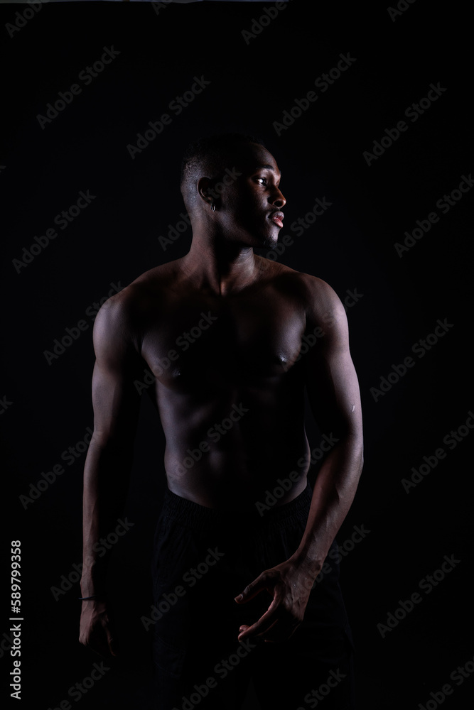 Portrait of an athletic african american man topless, black background