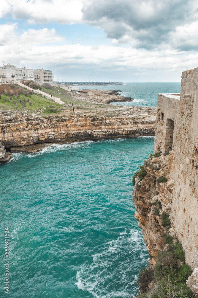 Polignano a Mare, Bari, Italy. Old town built on the rocky cliffs. Traveling concept background with old traditional houses, dramatic cloudy sky and beautiful view of Mediterranean Sea, vertical Polignano a Mare, Bari, Italy. Old town built on the rocky cliffs. Traveling concept background with old traditional houses, dramatic cloudy sky and beautiful view of Mediterranean Sea, vertical