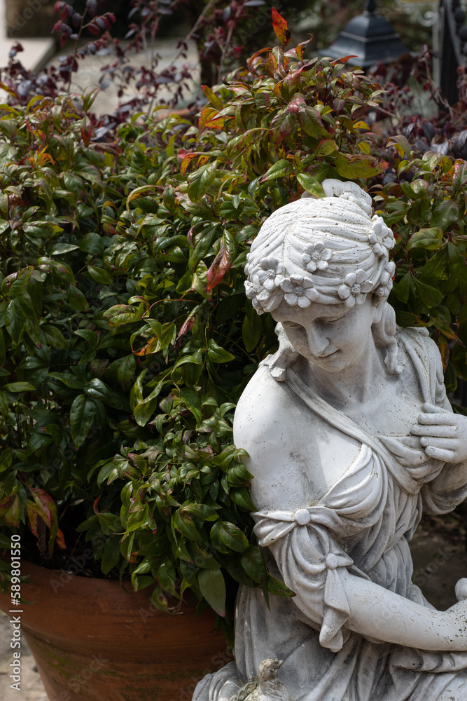 white rusty female statue placed next to potted plants white rusty female statue placed next to potted plants